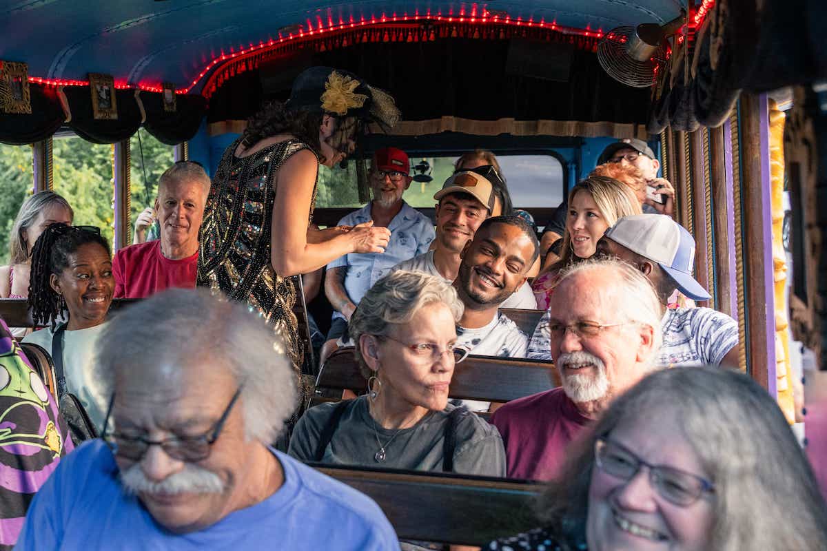 Charlotte Ghosted Tour - A costumed character is standing in the middle aisle of the LaZoom Bus, while passengers on either side are laughing